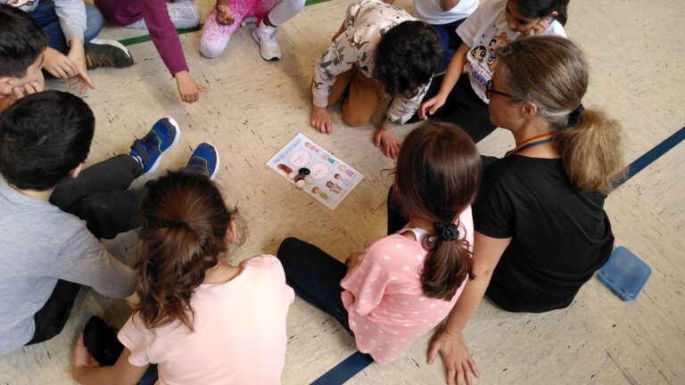 Kinder und eine Erwachsene sitzen in einem Kreis und schauen auf eine Karte
